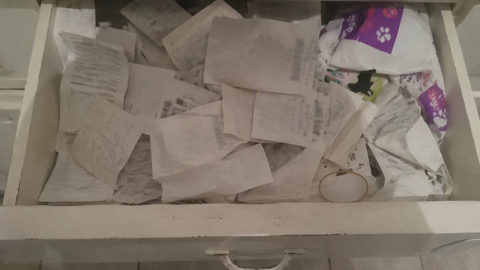 A kitchen drawer filled with crumpled vet and pet-shop receipts